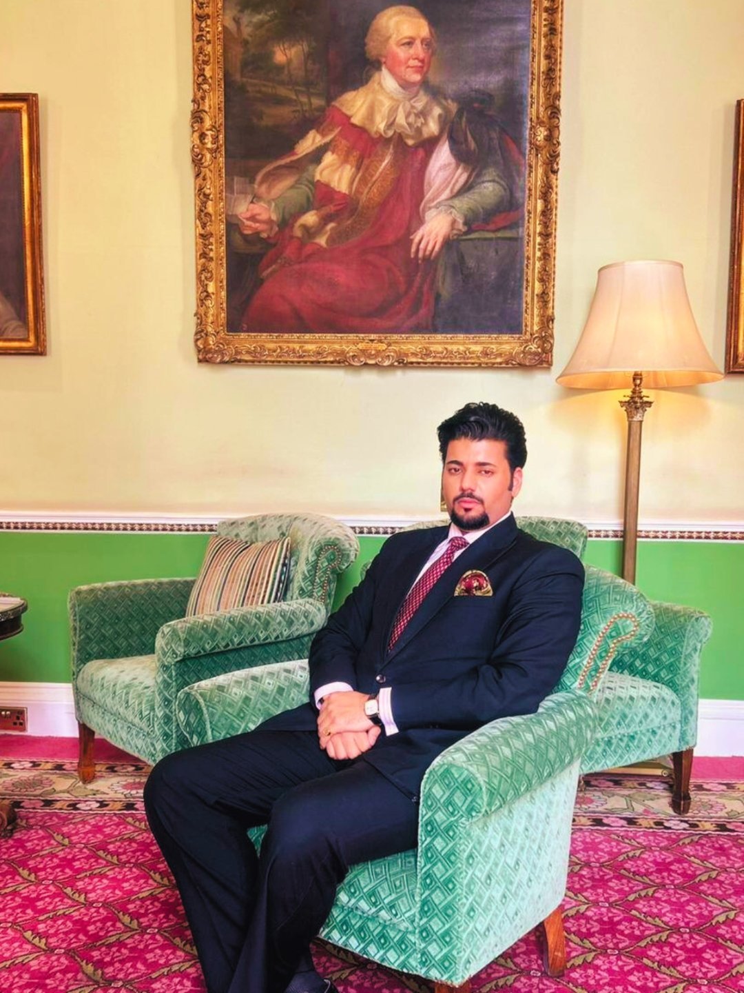 Manvedeep Singh seated beneath a portrait in oils